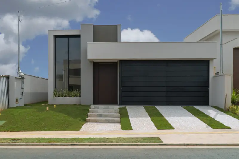 Fachada da Casa 24, no Jardins Bolonha, com portão de garagem escuro e jardim na frente