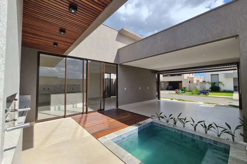 Área da piscina da Casa Verato, no Jardins Bolonha, com deck de madeira e portas de vidro